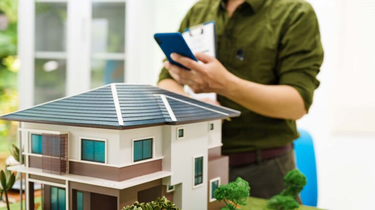 mann_mit_mobiltelefon_vor_modellhaus