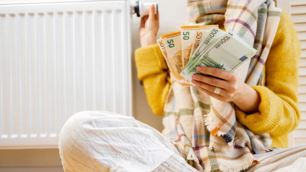 frau_vor_heizung_mit_euros_in_hand