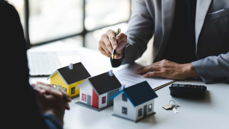 immobilienmakler_zeigt_auf_haus_modelle