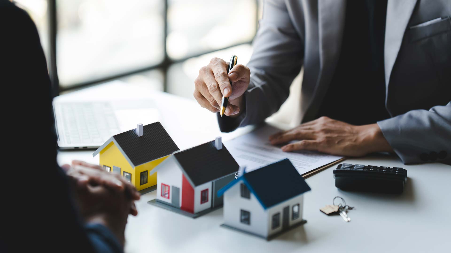 immobilienmakler_zeigt_auf_haus_modelle
